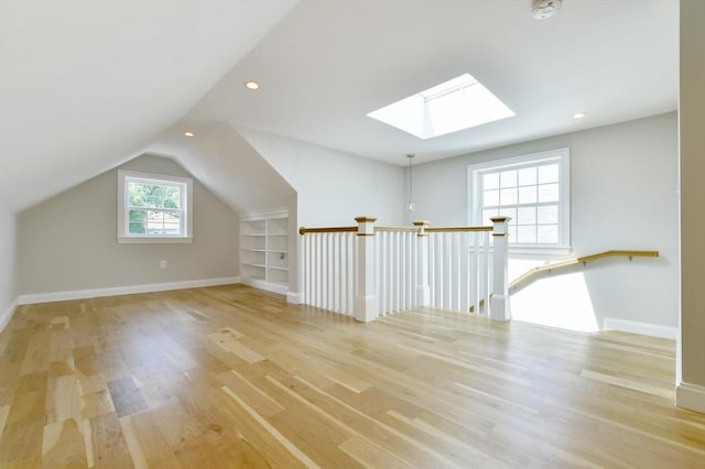 bonus room with a skylight, light wood finished floors, lofted ceiling, baseboards, and recessed lighting