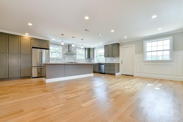 kitchen featuring appliances with stainless steel finishes, wall chimney exhaust hood, light countertops, crown molding, and backsplash