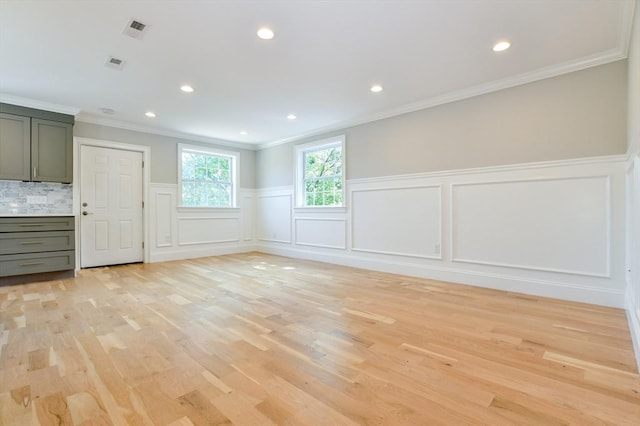 spare room featuring a decorative wall, light wood-type flooring, crown molding, a wainscoted wall, and recessed lighting