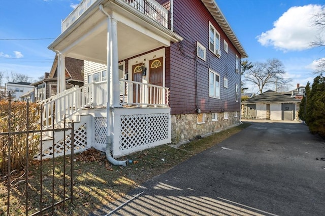 view of side of property with a garage, a porch, and an outdoor structure