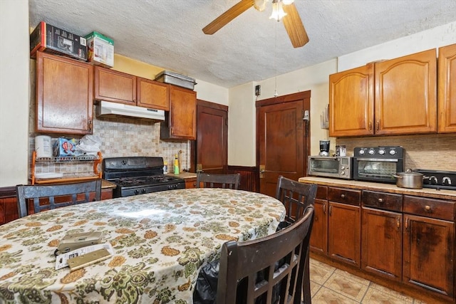 kitchen with a textured ceiling, ceiling fan, light tile patterned floors, backsplash, and black gas range oven