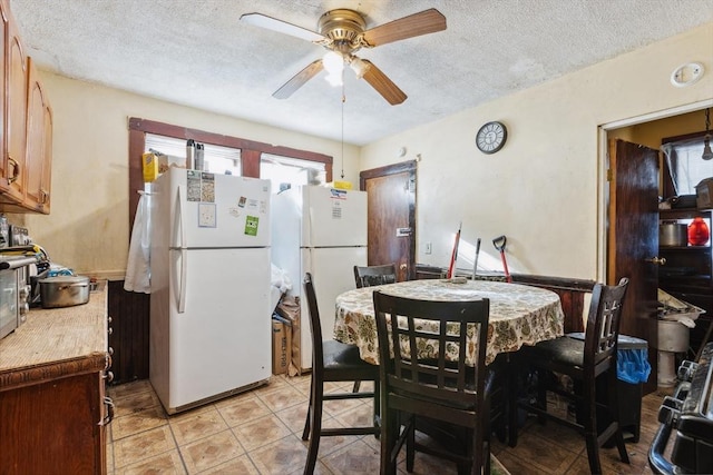 dining space with a textured ceiling, ceiling fan, and light tile patterned floors