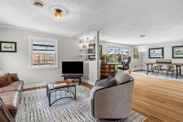 living room with healthy amount of natural light, crown molding, wood finished floors, and baseboards