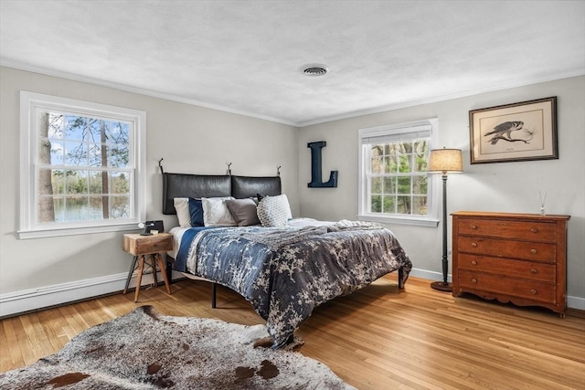 bedroom with crown molding, baseboards, light wood finished floors, and a baseboard radiator
