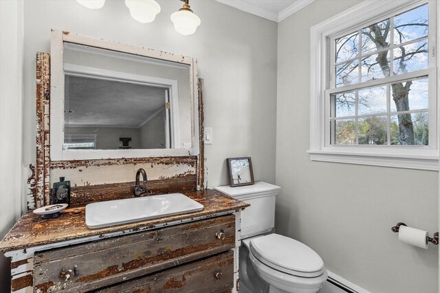 bathroom featuring toilet, vanity, crown molding, baseboard heating, and baseboards