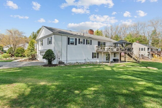 back of house with stairs, a wooden deck, a chimney, an attached garage, and asphalt driveway
