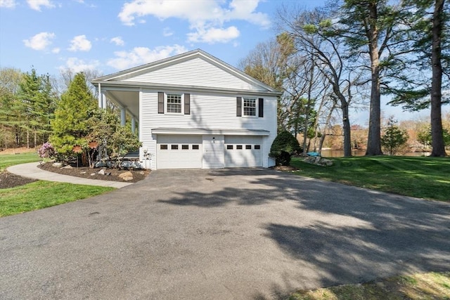 view of side of property with asphalt driveway, an attached garage, and a lawn