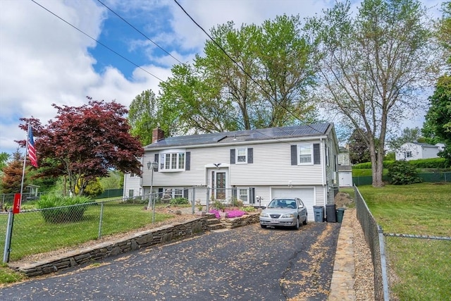 raised ranch with asphalt driveway, an attached garage, and a chimney