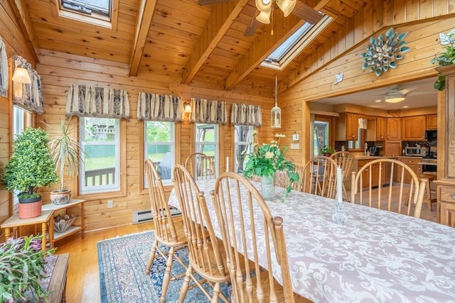 dining space with a skylight, a ceiling fan, wooden walls, light wood-type flooring, and wood ceiling