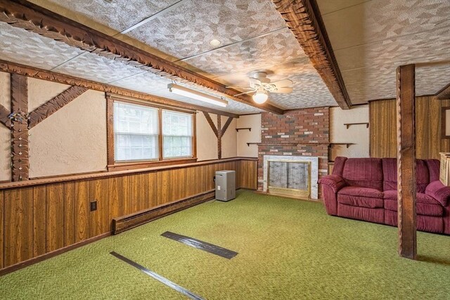 interior space with a baseboard radiator, wood walls, ceiling fan, carpet floors, and wainscoting