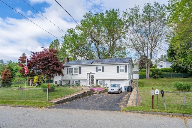 raised ranch featuring asphalt driveway, an attached garage, and a chimney