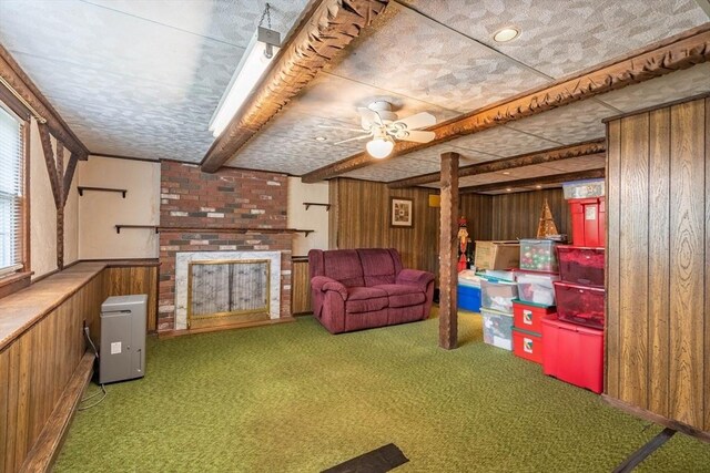 living room featuring wood walls, carpet flooring, a ceiling fan, and a fireplace