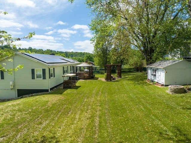 view of grassy yard with a gazebo, a fire pit, and a wooden deck