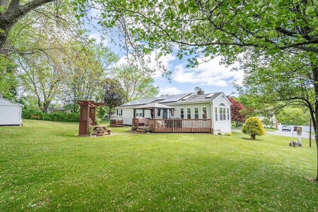 back of house featuring an outdoor fire pit, a deck, and a lawn