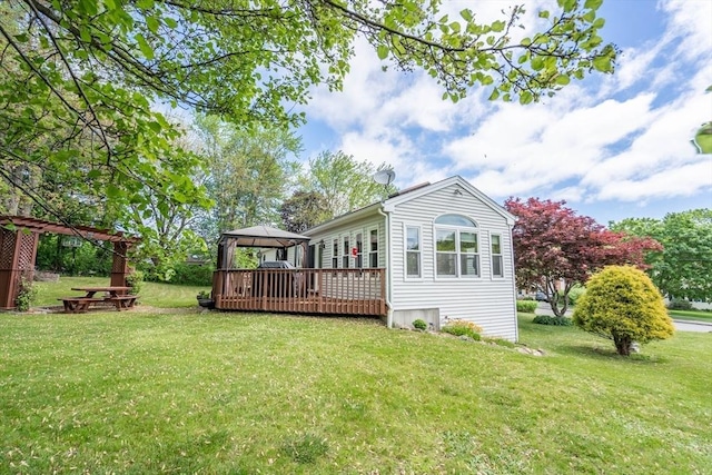 rear view of property featuring a gazebo, a deck, and a yard