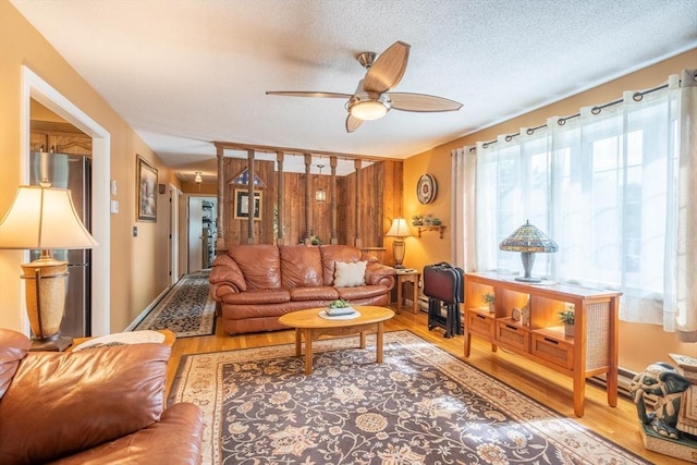 living room featuring ceiling fan, wood finished floors, and a textured ceiling