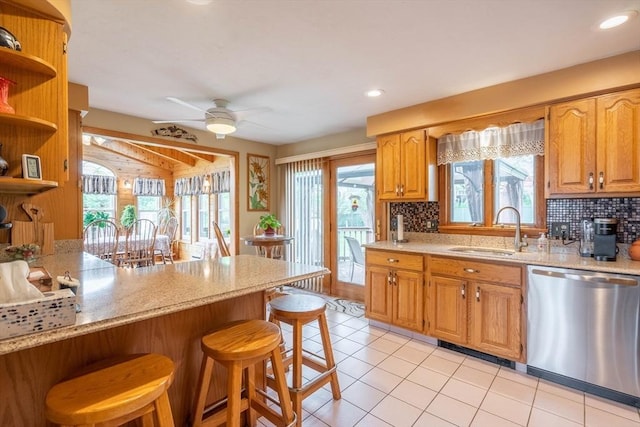 kitchen with stainless steel dishwasher, a sink, a breakfast bar, decorative backsplash, and recessed lighting