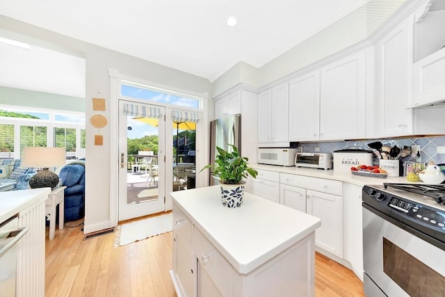 8 Barn Ln, Gloucester, MA 01930 - kitchen featuring appliances with stainless steel finishes, light wood-style floors, light countertops, white cabinets, and a kitchen island