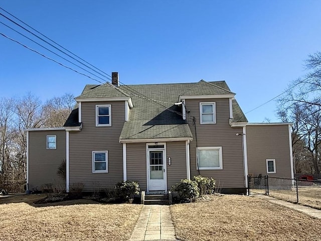 view of front of home featuring entry steps, a gate, fence, and a chimney