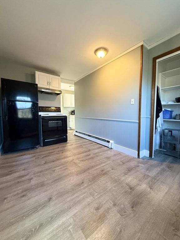 kitchen featuring light wood-style flooring, electric range oven, a baseboard heating unit, freestanding refrigerator, and under cabinet range hood