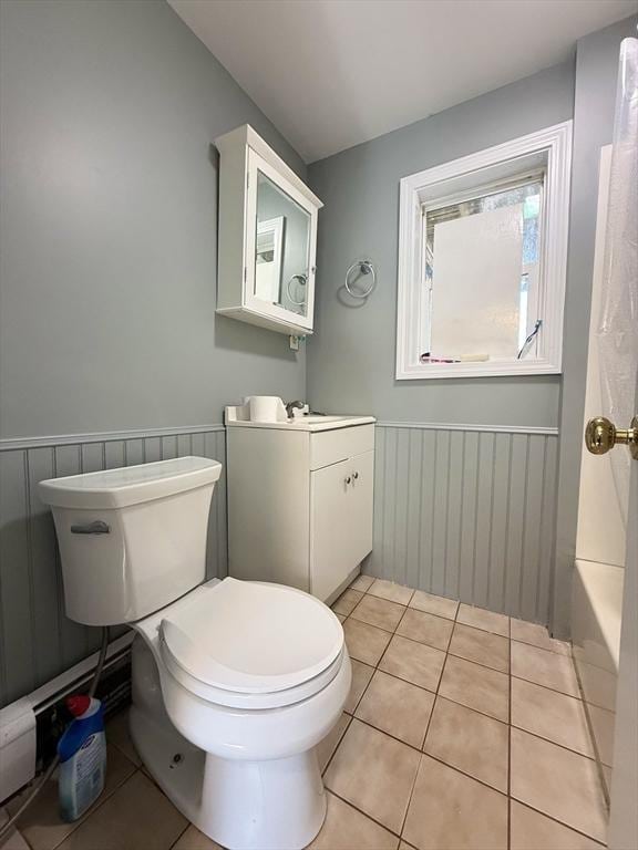 bathroom featuring toilet, tile patterned floors, vanity, and wainscoting