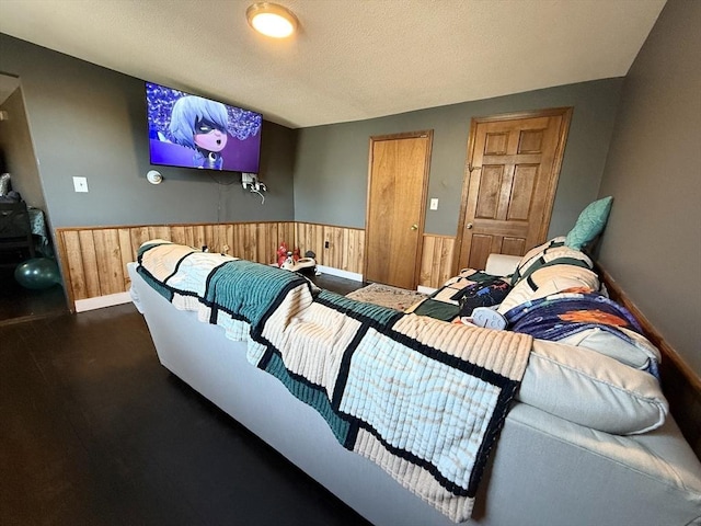 home theater room with a wainscoted wall, a textured ceiling, and wood walls