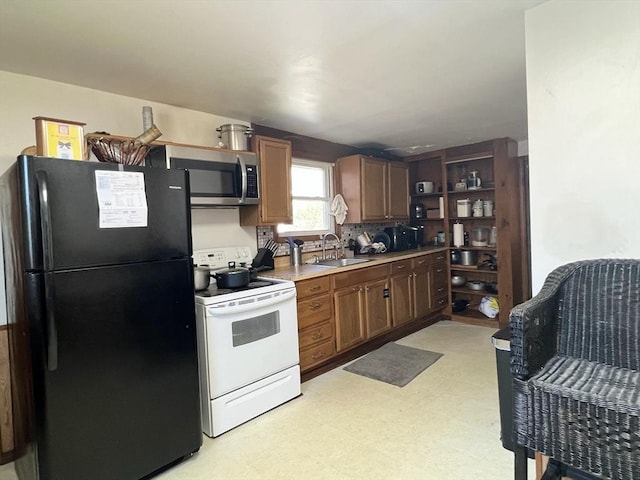 kitchen with electric stove, light floors, stainless steel microwave, freestanding refrigerator, and a sink