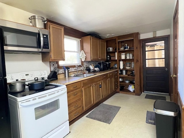 kitchen featuring light floors, open shelves, white electric range oven, stainless steel microwave, and a sink