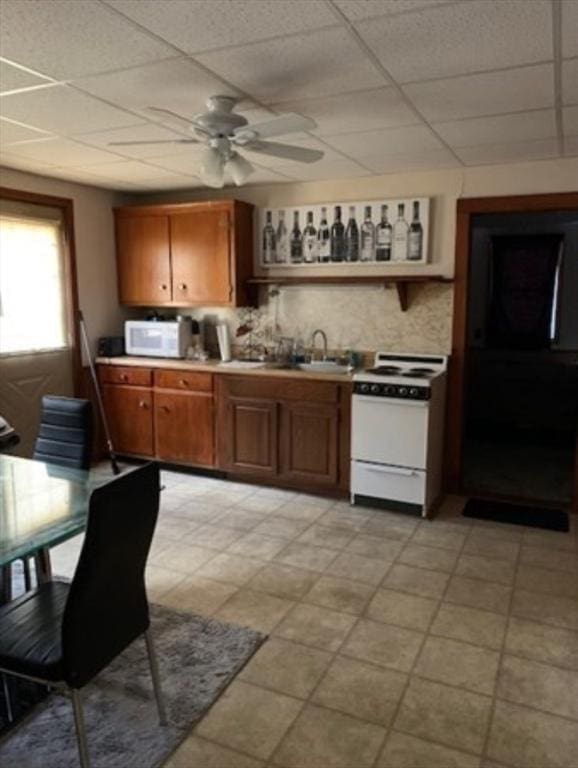 kitchen with brown cabinetry, white appliances, a sink, and tasteful backsplash