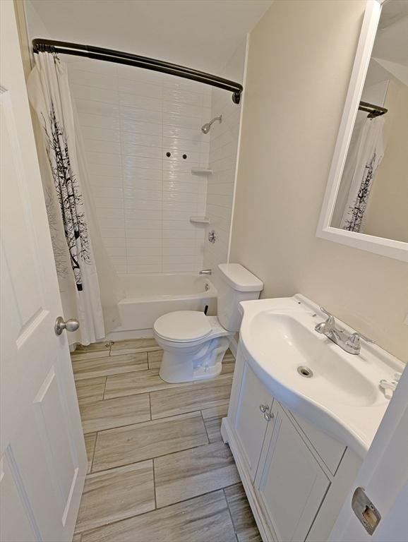 bathroom with vanity, shower / bath combination with curtain, and toilet