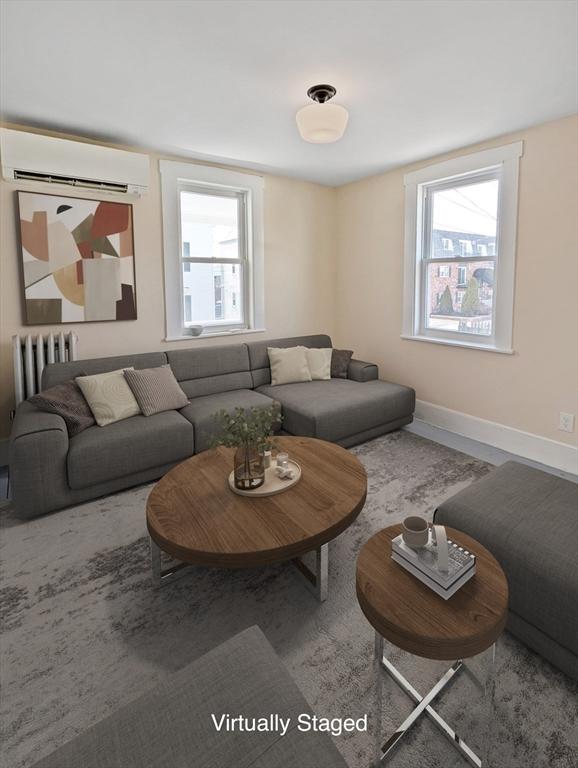 living room with radiator, baseboards, and a wall mounted air conditioner