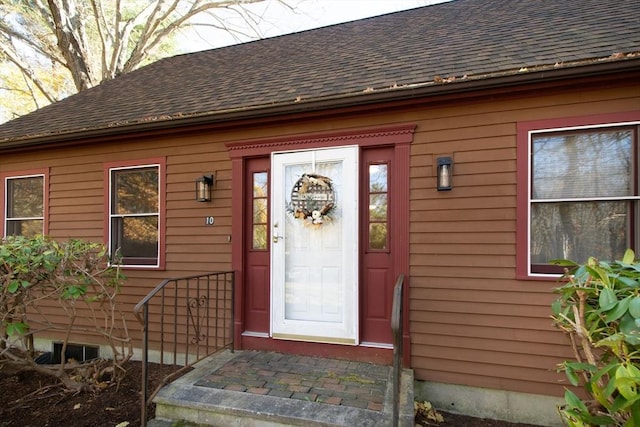 doorway to property featuring roof with shingles