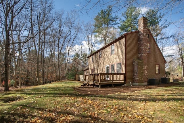 view of property exterior with a chimney, central AC, a deck, and a lawn