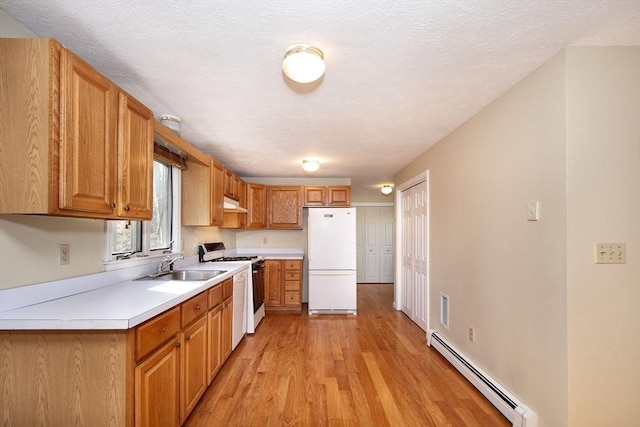 kitchen with freestanding refrigerator, gas range oven, light countertops, a baseboard heating unit, and a sink