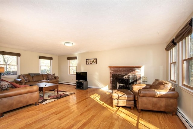 living room with light wood-style flooring, a fireplace, a baseboard heating unit, and baseboards