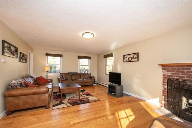 living area with light wood finished floors, a baseboard radiator, a fireplace, and a healthy amount of sunlight