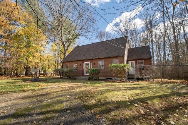 cape cod home with a front lawn and fence