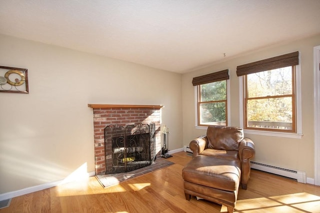 living area with a brick fireplace, baseboards, baseboard heating, and wood finished floors