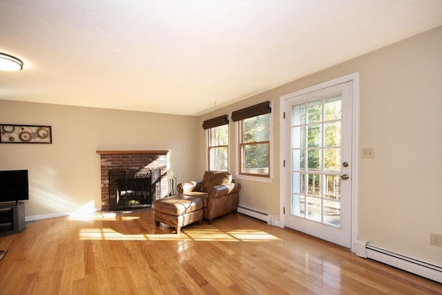 living room with a fireplace, a baseboard heating unit, and wood finished floors