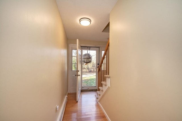 entryway with light wood-style floors, a baseboard radiator, stairway, and baseboards