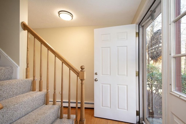 foyer with light wood finished floors, stairs, and a baseboard heating unit