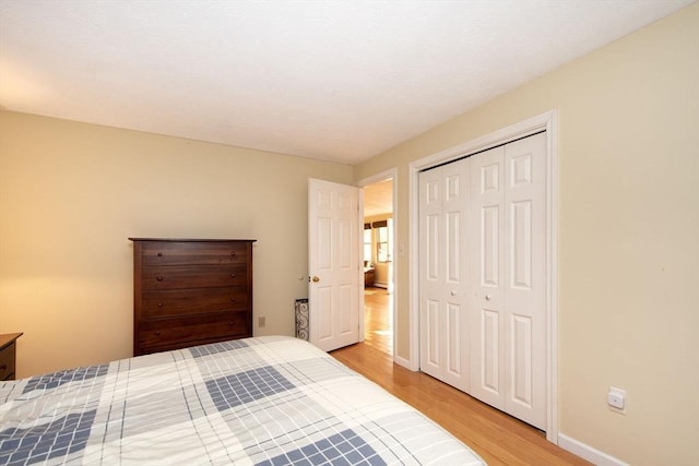 bedroom featuring a closet, baseboards, and light wood finished floors