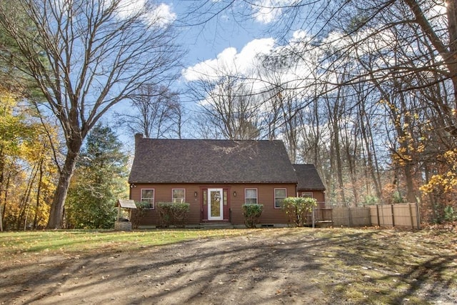 new england style home featuring roof with shingles and fence