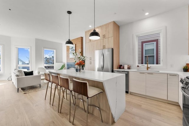 kitchen featuring a center island, sink, decorative light fixtures, a breakfast bar, and stainless steel appliances