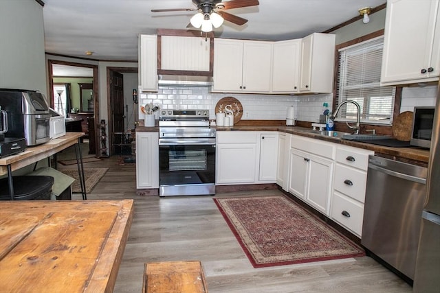 kitchen with tasteful backsplash, appliances with stainless steel finishes, light wood-style floors, white cabinets, and a sink