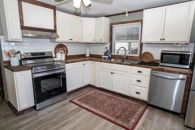 kitchen featuring under cabinet range hood, a sink, stainless steel appliances, white cabinets, and light wood finished floors