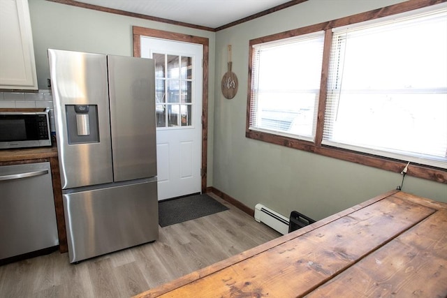 kitchen featuring stainless steel appliances, light wood-style floors, crown molding, a baseboard radiator, and baseboards