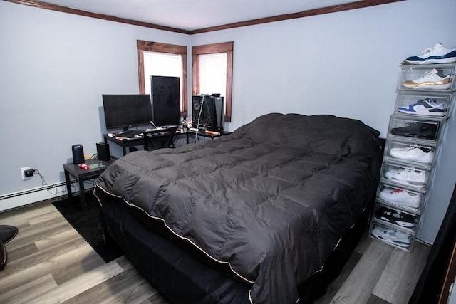 bedroom with a baseboard heating unit, crown molding, and wood finished floors