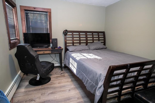 bedroom with baseboard heating and wood finished floors