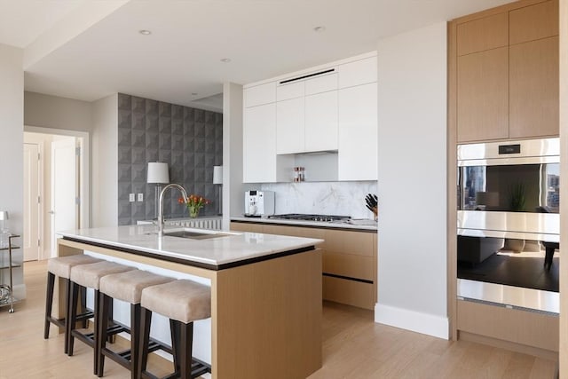 kitchen featuring sink, white cabinetry, a kitchen breakfast bar, an island with sink, and stainless steel appliances